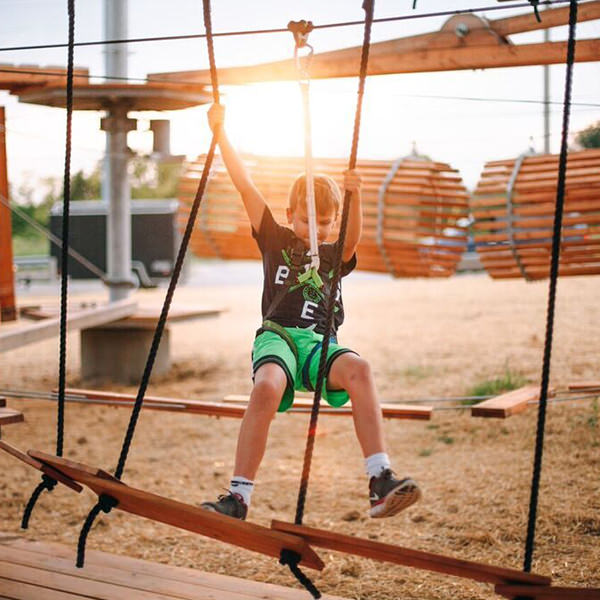 Kid hanging to a rope in adventure park