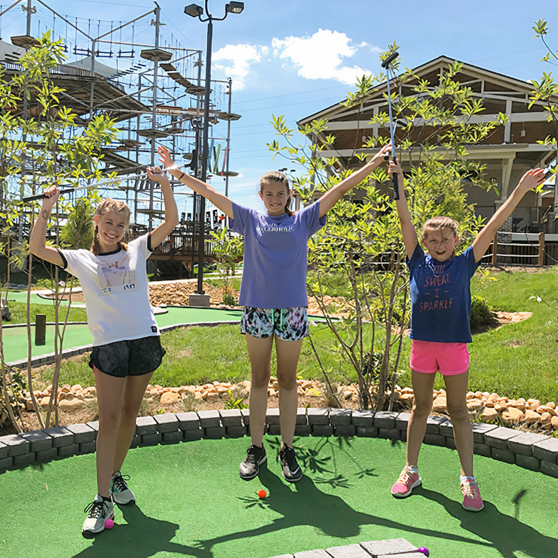Three girls with their hands up high having fun at Soar Adventures