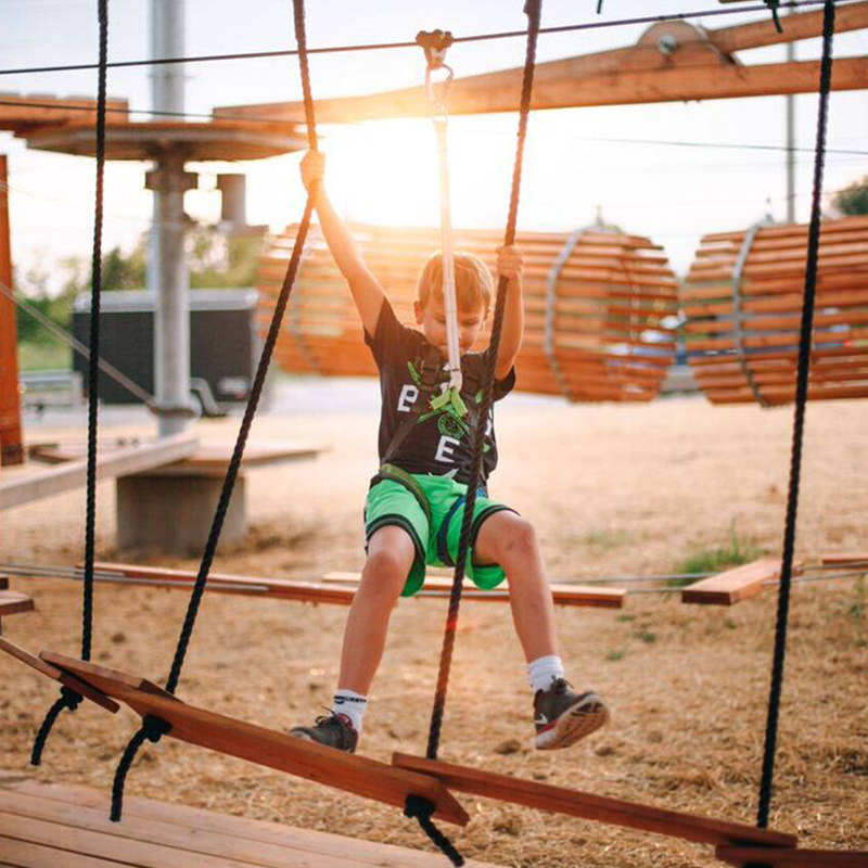 Kid hanging to a rope in adventure park